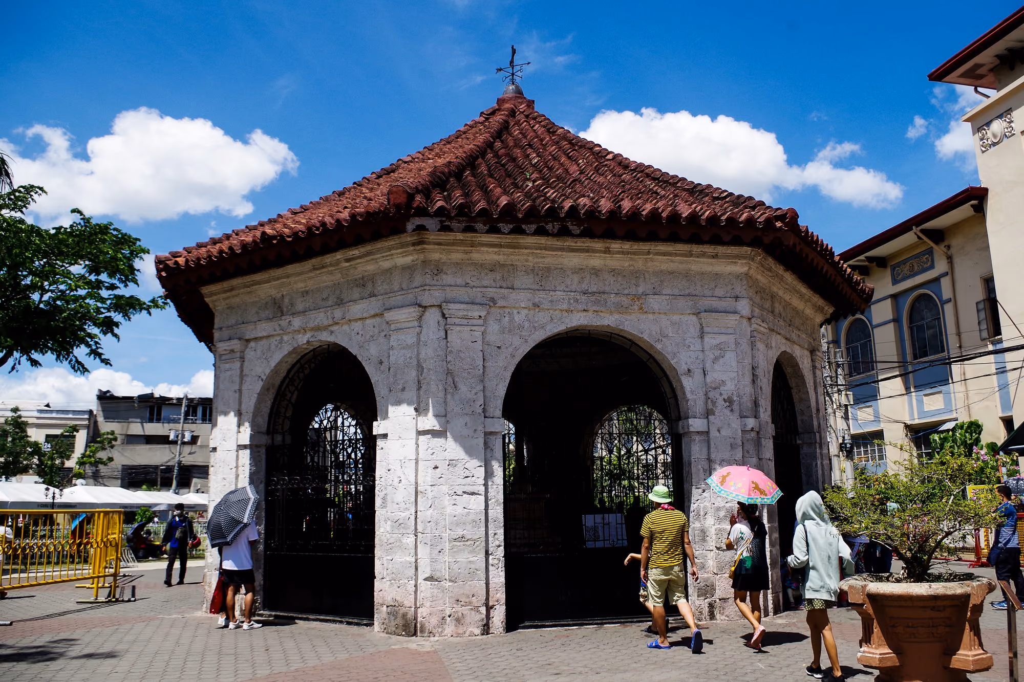 Magellan's Cross in its red-roofed pavilion in Cebu City, under a blue sky.