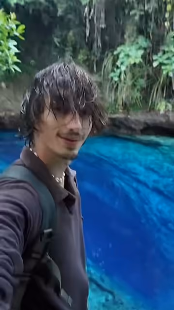 Robert standing beside the bright blue water of the Enchanted River, with tropical forest behind him.