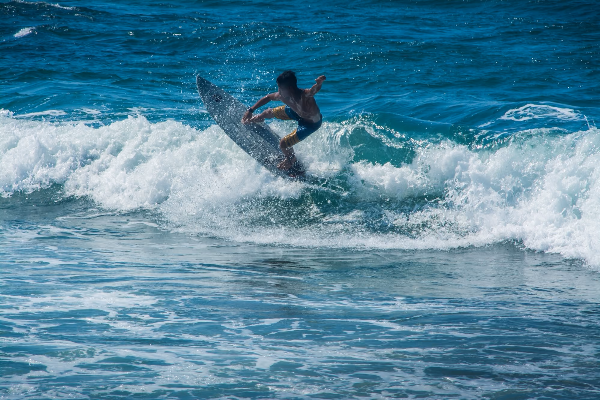 A surfer riding a green-blue wave off San Juan, La Union.