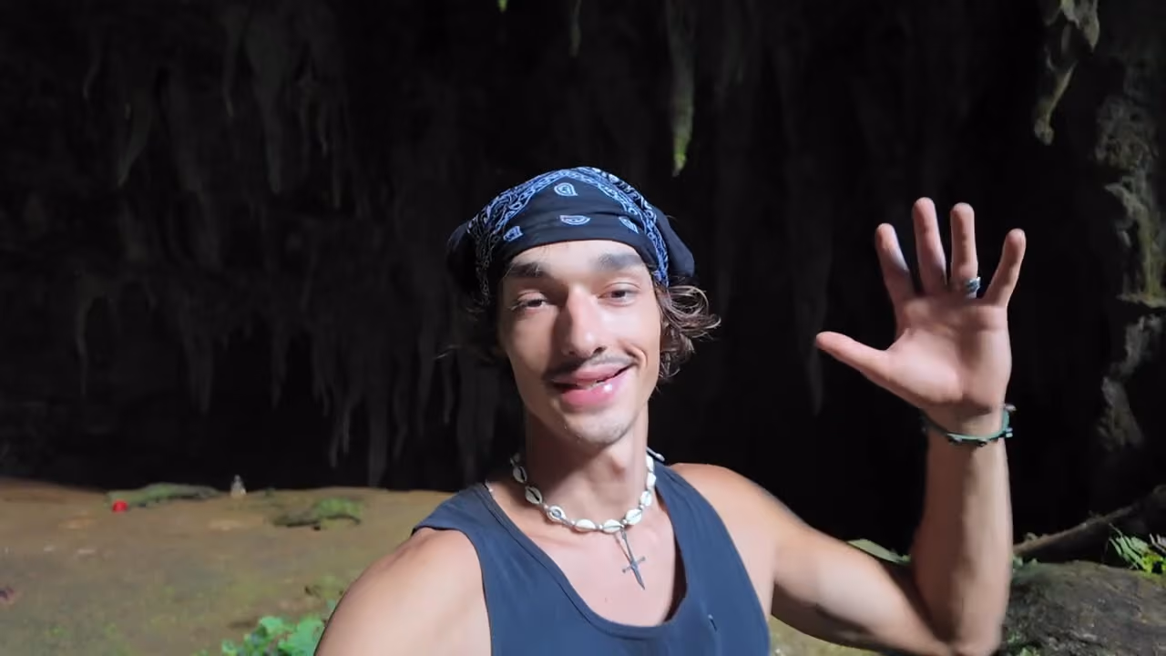 Robert standing inside Langun-Gobingob cave, waving at the camera, the dark cave wall behind him.