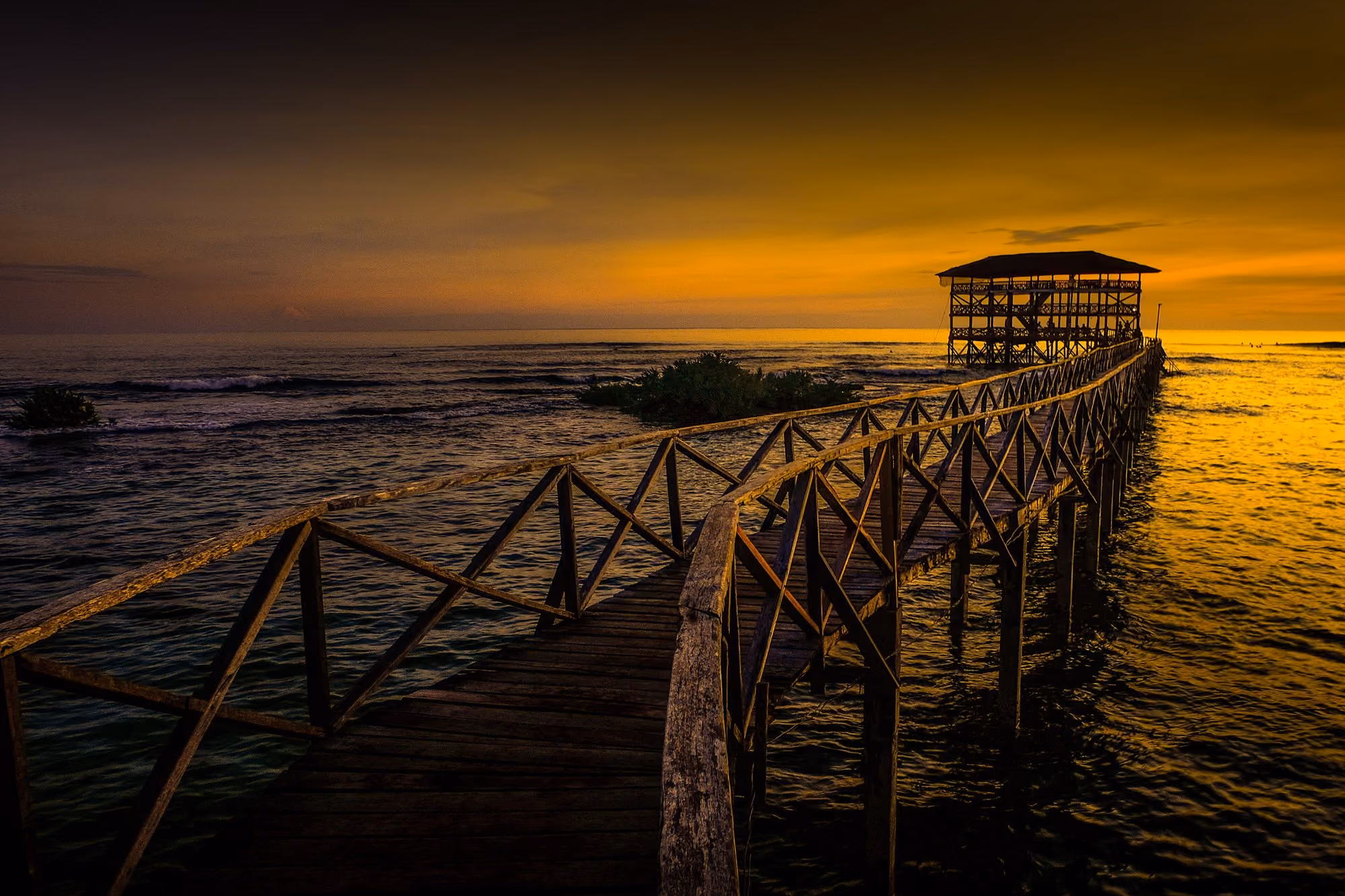 The wooden boardwalk running out over the reef to the lookout hut at Cloud 8, Siargao, at sunset.