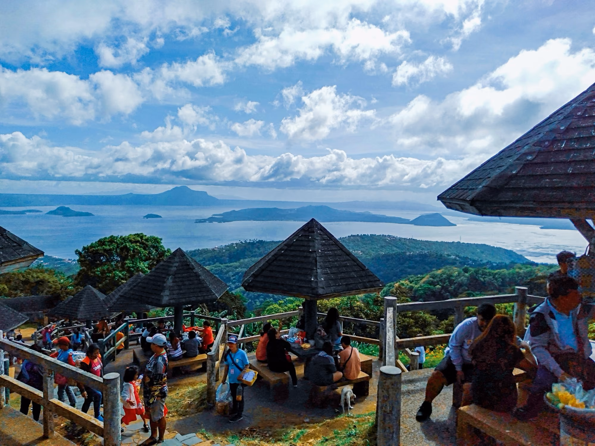 Taal Lake seen from the Tagaytay Picnic Grove, with thatched huts in the foreground.